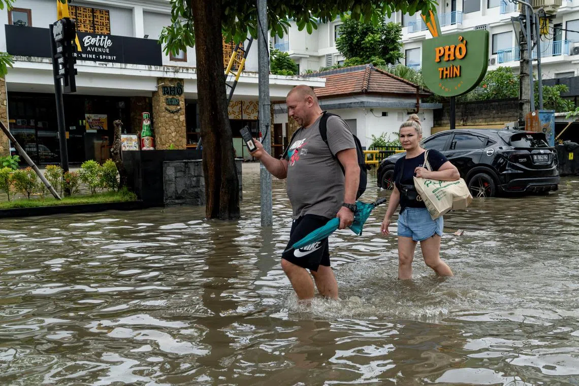 印尼旅游胜地之一的峇厘岛遭遇暴雨，有游客涉水穿过被洪水淹没的道路。（路透社）