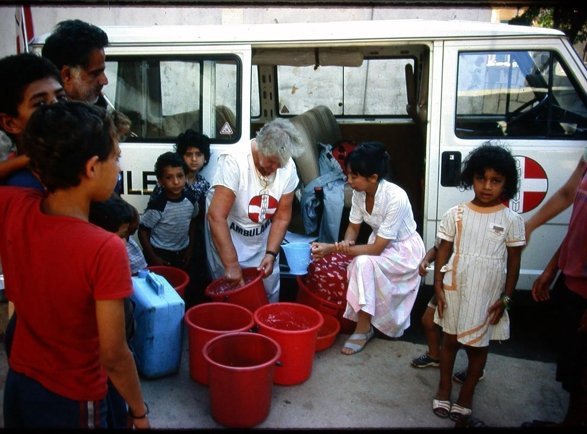 1988年，洪瑞钗（右二）和巴勒斯坦人医药援助会的义工派发牛奶给西贝鲁特难民庇护所的儿童。（受访者提供）