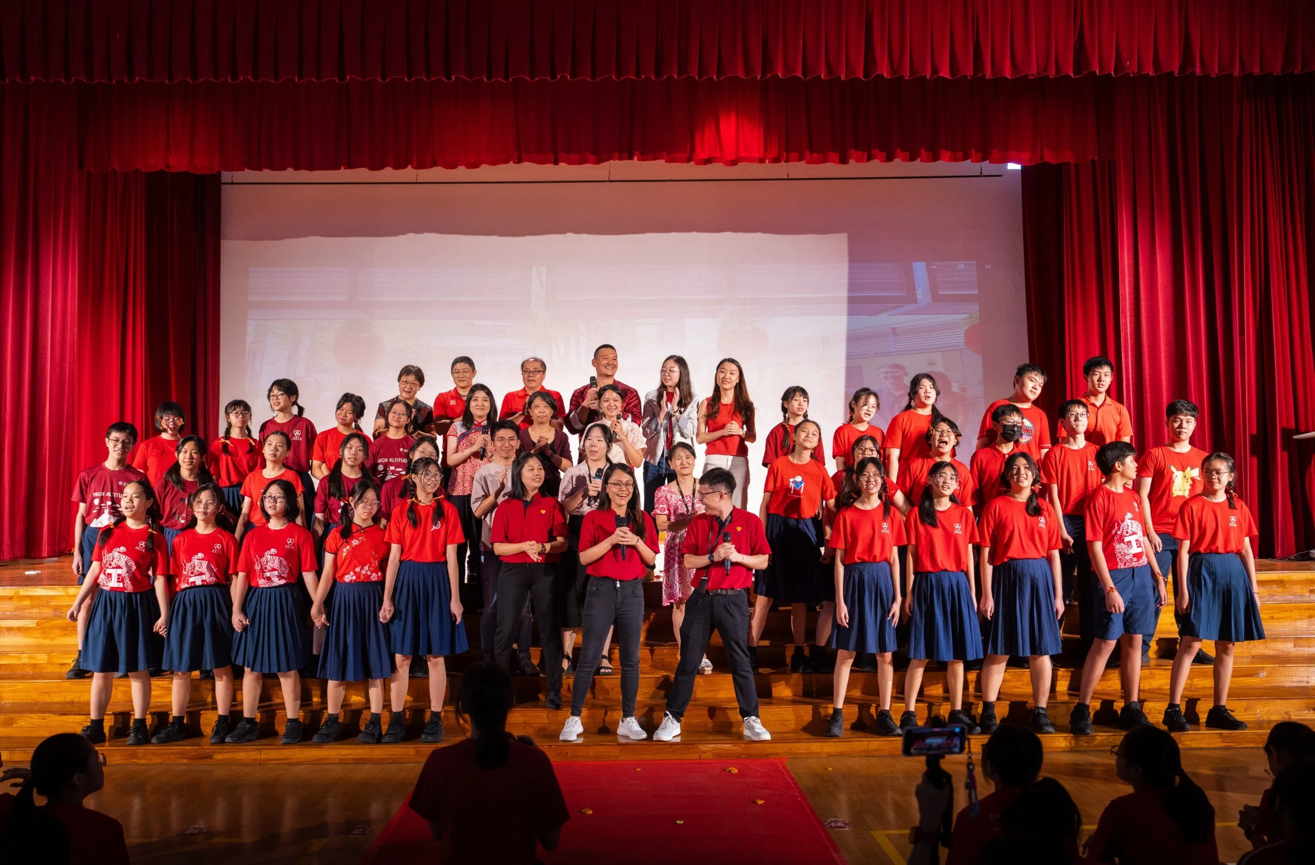 南侨合唱团和师生在庆祝会上合唱改编版《大地回春》，礼堂里充满欢声笑语。（南侨中学刘宇泽摄）