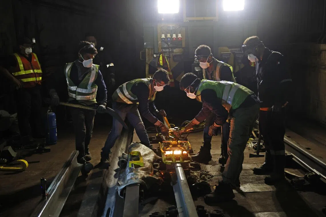 工程人员以化学焊接方式连接新旧铁轨，确保轨道顺畅衔接并符合运营标准。（陈渊庄摄）