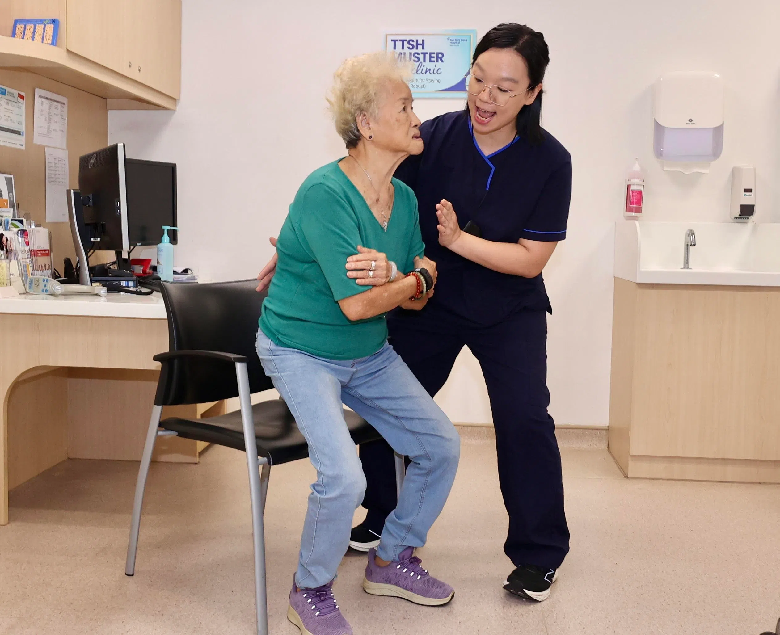 陈亚珊（左）在陈笃生医院首席物理治疗师马舒瑜（右）的指导下，进行坐站练习。（邬福梁摄）