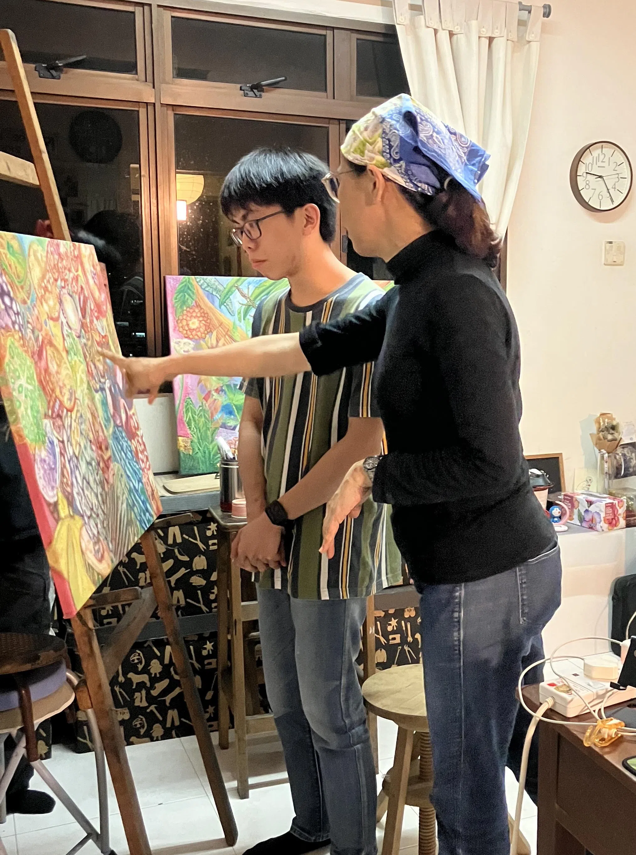 许信（左）与导师陈玲娜讨论画作。（新加坡特殊才艺协会提供）