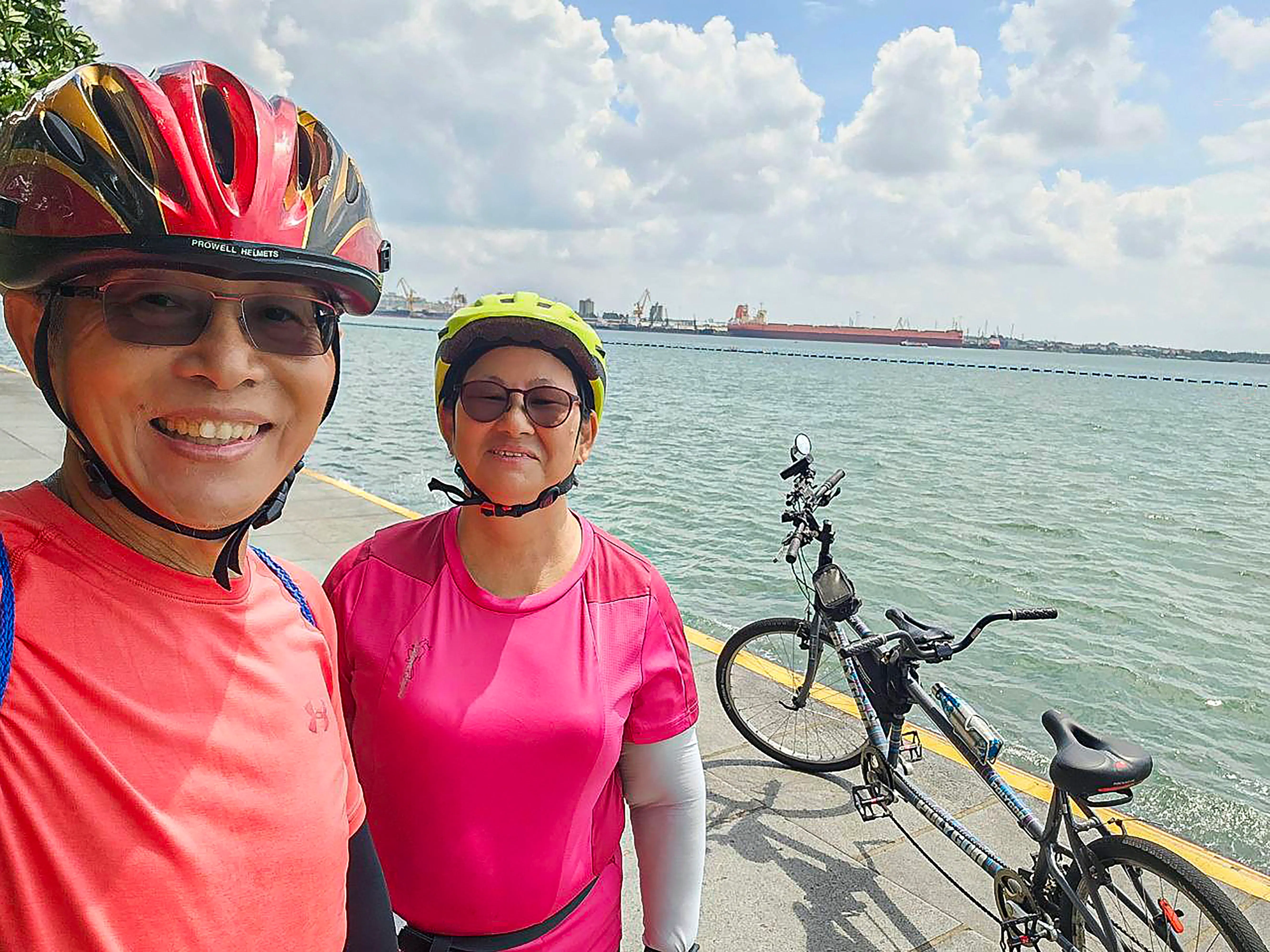 李庆贤（左）和妻子陈彩群，每周四五次骑着双人脚踏车到处走，不时一起从三巴旺一路骑到科尼岛。（受访者提供）