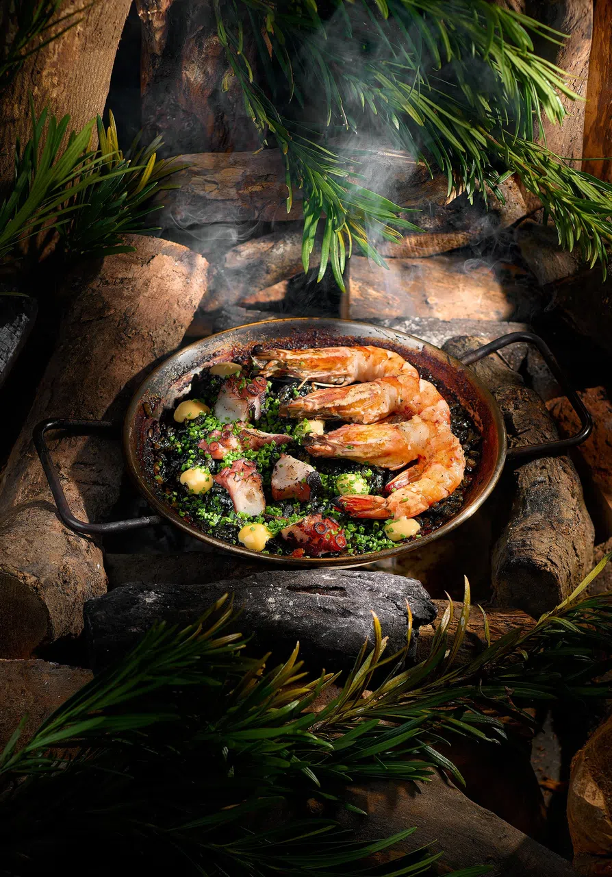 墨鱼汁海鲜烩饭搭配烤虾和章鱼，鲜香四溢。（餐馆提供）