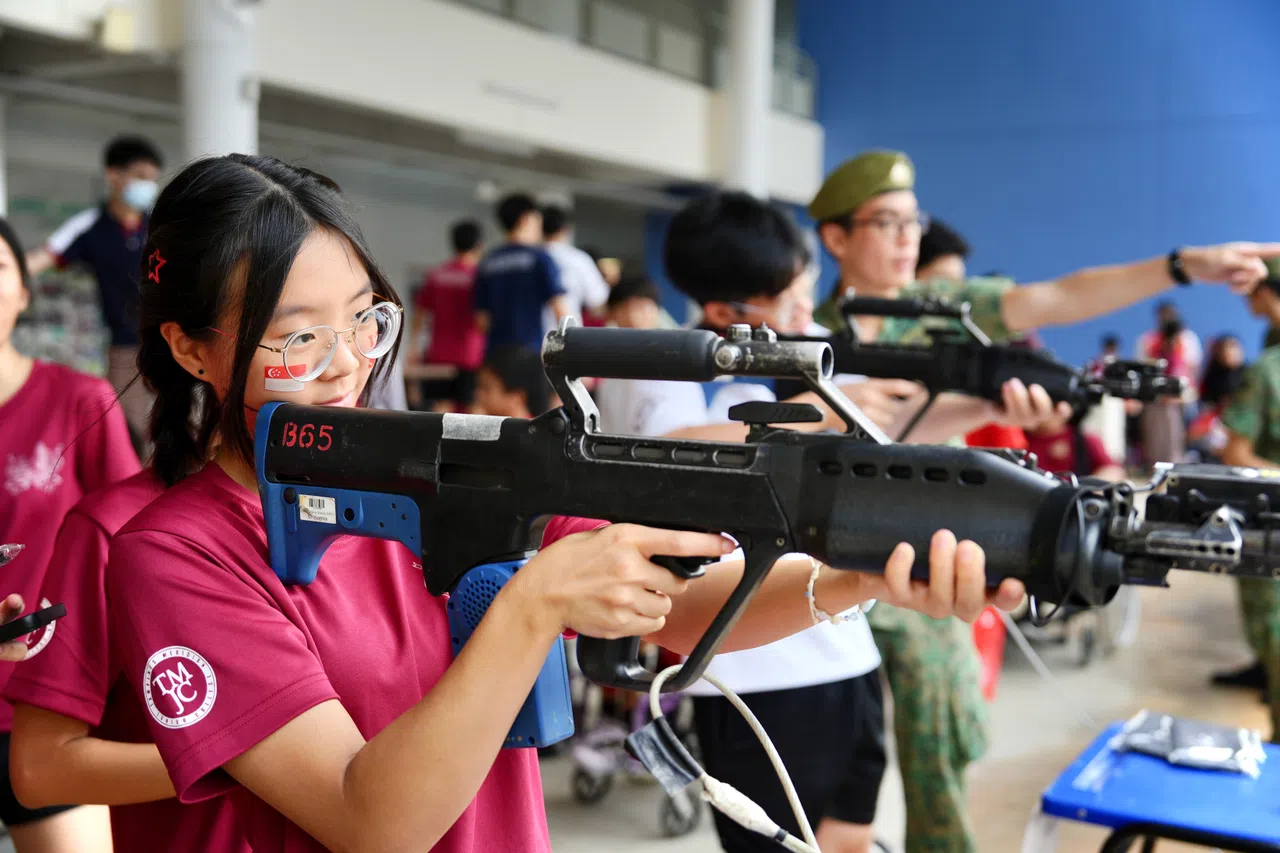 学生在新加坡步兵团第三营设立的展示摊位尝试使用步枪。（淡滨尼美廉初院摄影俱乐部提供）