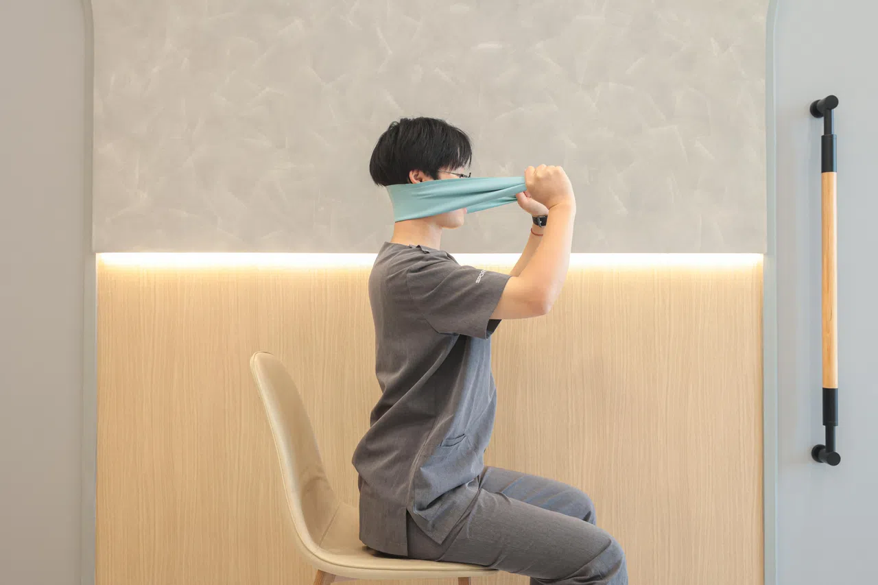 弹力带中间部分搁在颈部后上方。（李冠卫摄）