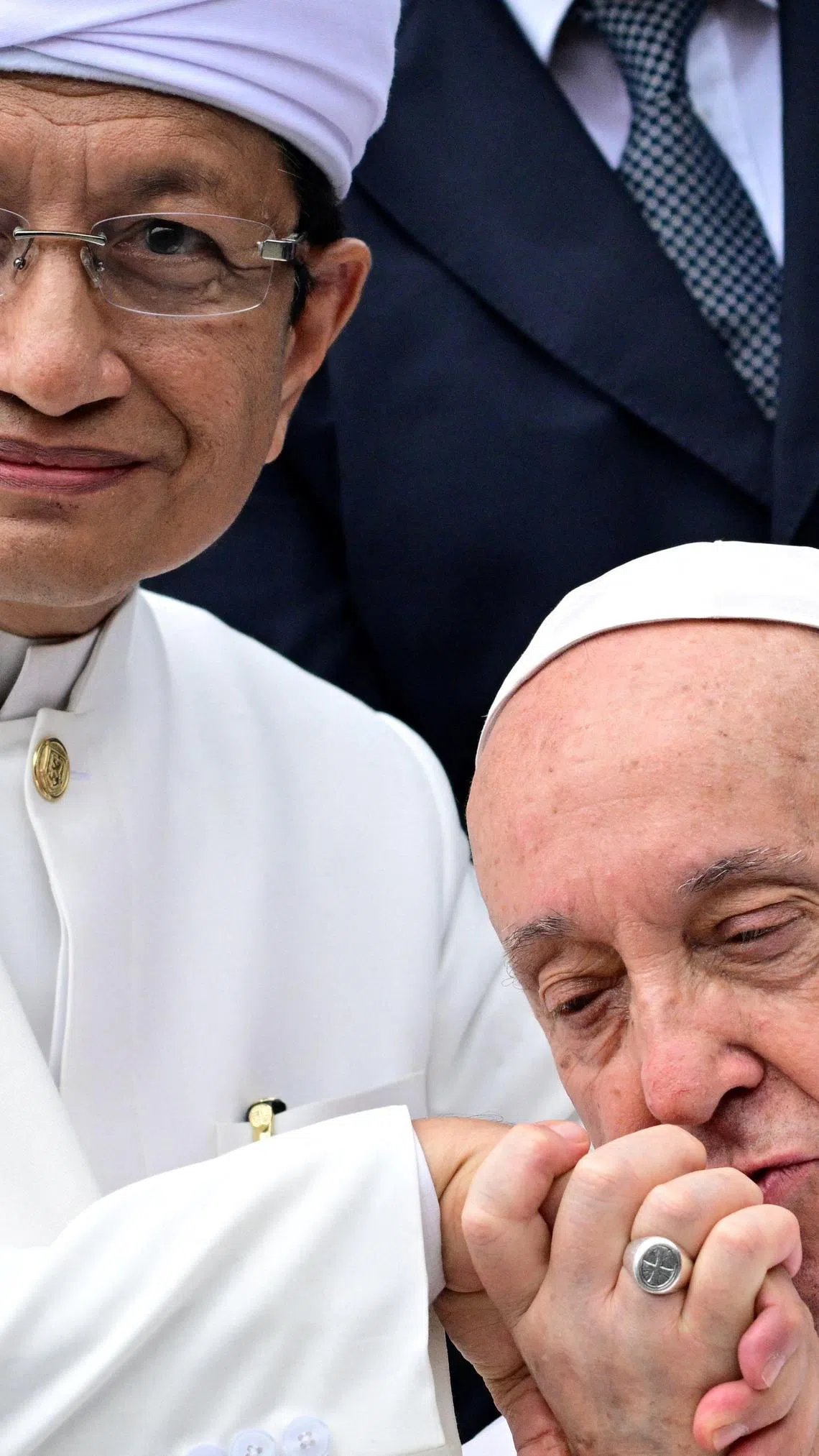 方济各（右）离开伊斯蒂克拉尔回教堂前，亲吻印尼回教大教长纳沙鲁丁的手背。（法新社）