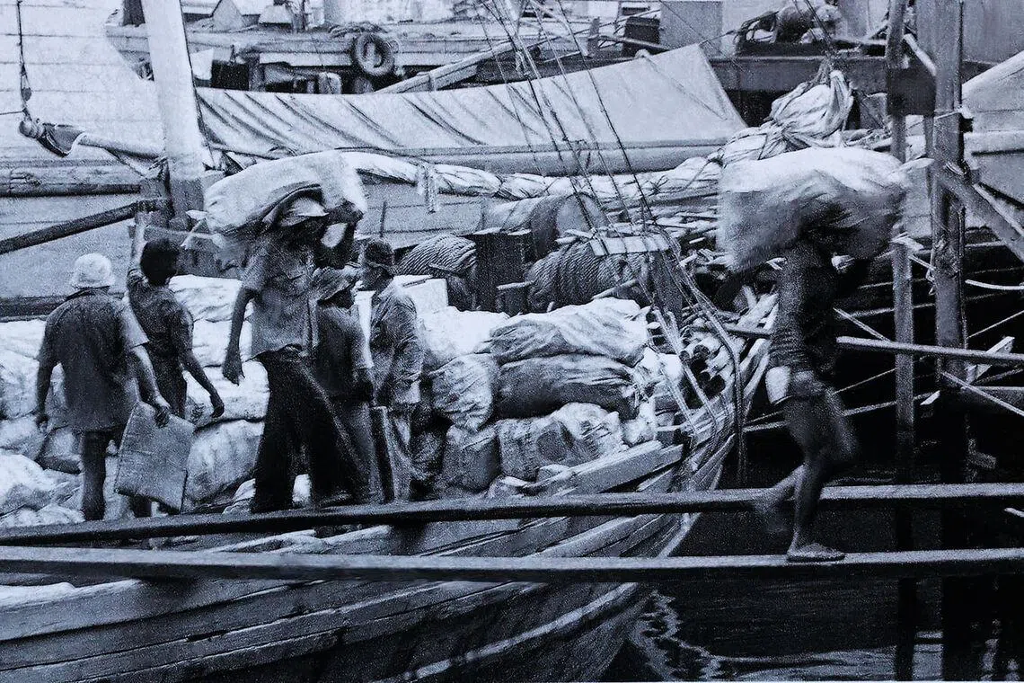 驳船码头劳工扛着几十公斤重的货物，轻巧地走过窄窄木板。（雷福胜摄）