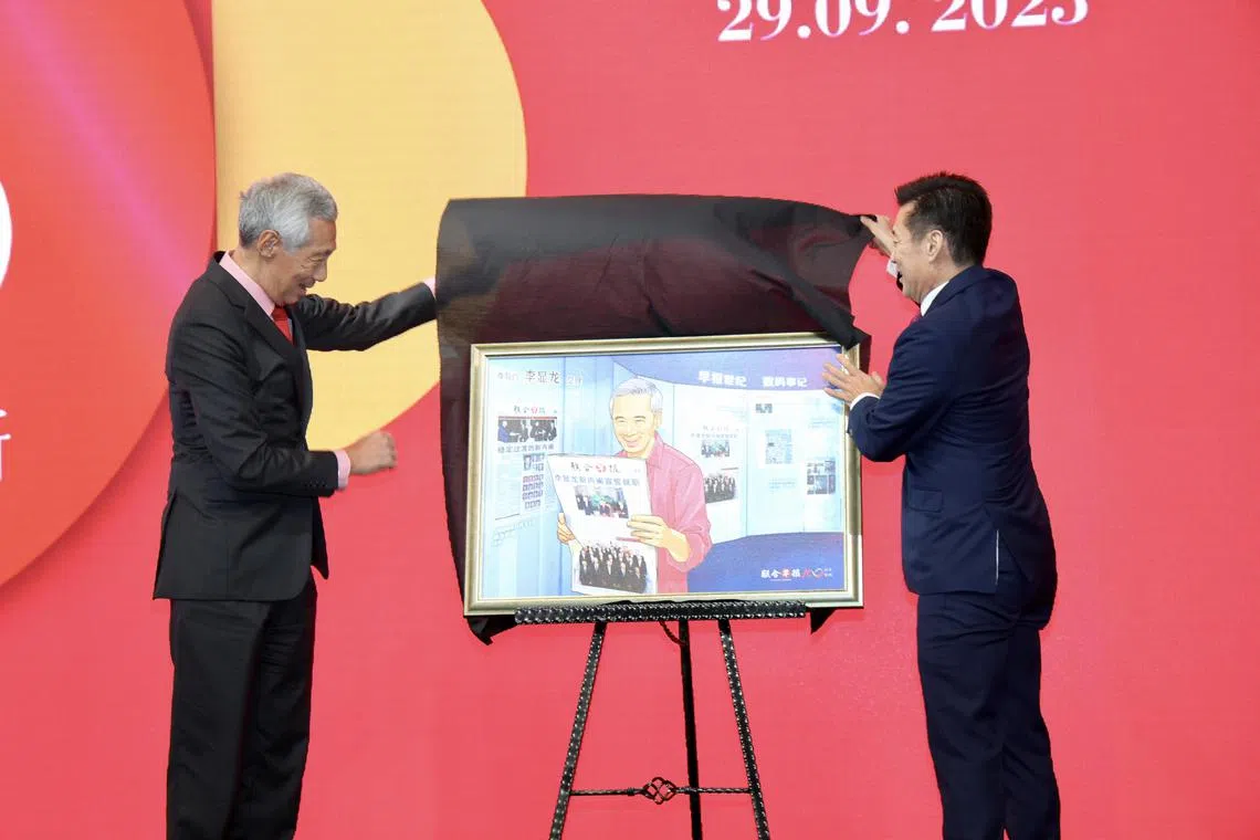 李显龙总理（左）说，他是《联合早报》的读者，每天都会阅读电子版的报纸。2023年早报100晚宴，《联合早报》总编辑吴新迪为他献上由早报视觉部构思的特殊数码画作。作品中有李总理出生日1952年2月10日的《南洋商报》和《星洲日报》封面；他手上拿着的则是2004年8月13日的《联合早报》，封面是他出任总理时组建的新内阁合照。（档案照片）