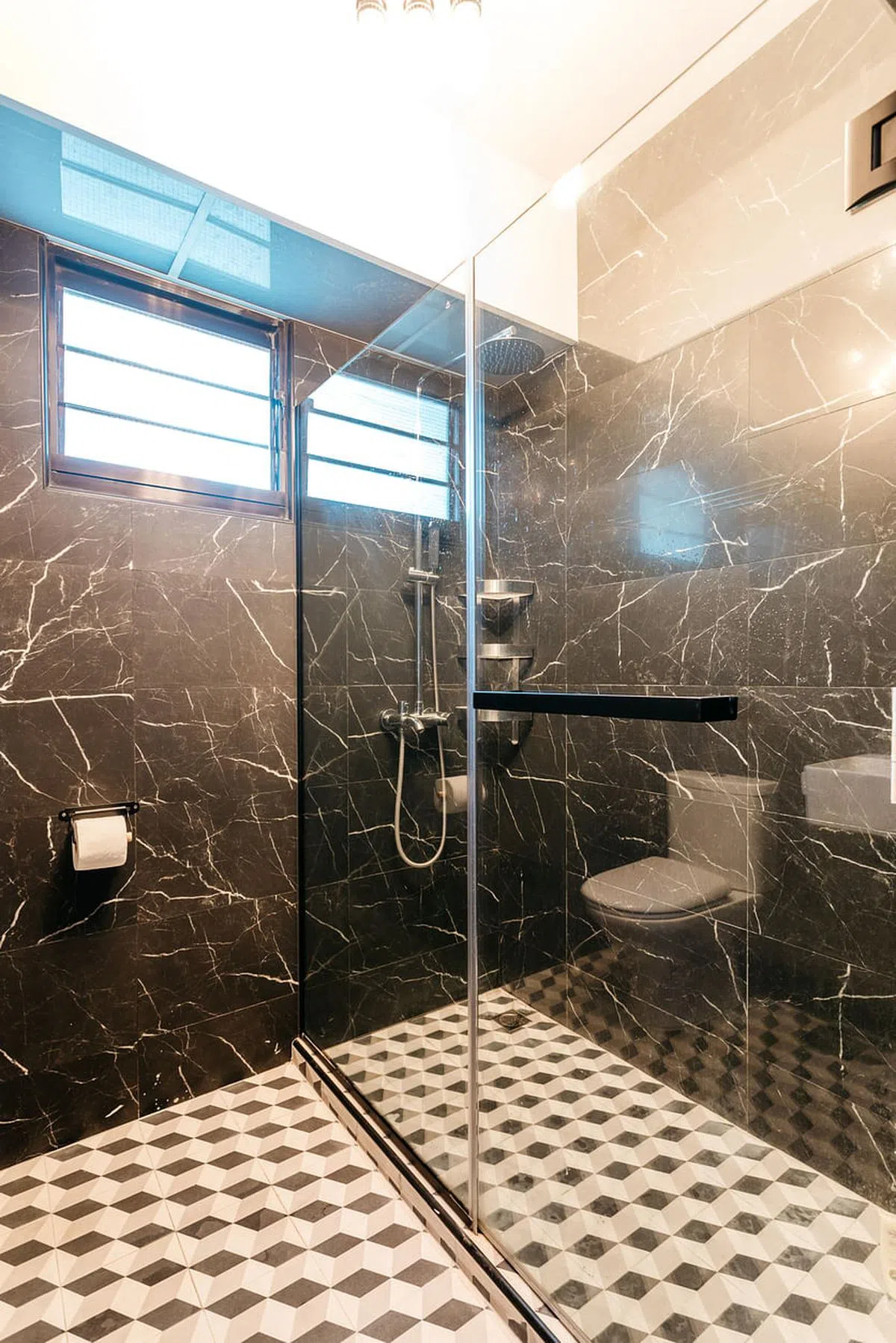 用黑色大理石装修的卫浴间，地砖的三色菱形图案有3D效果，给人踩在阶梯上的错觉，打破了黑的霸气。（木美室内设计工作室提供图片）