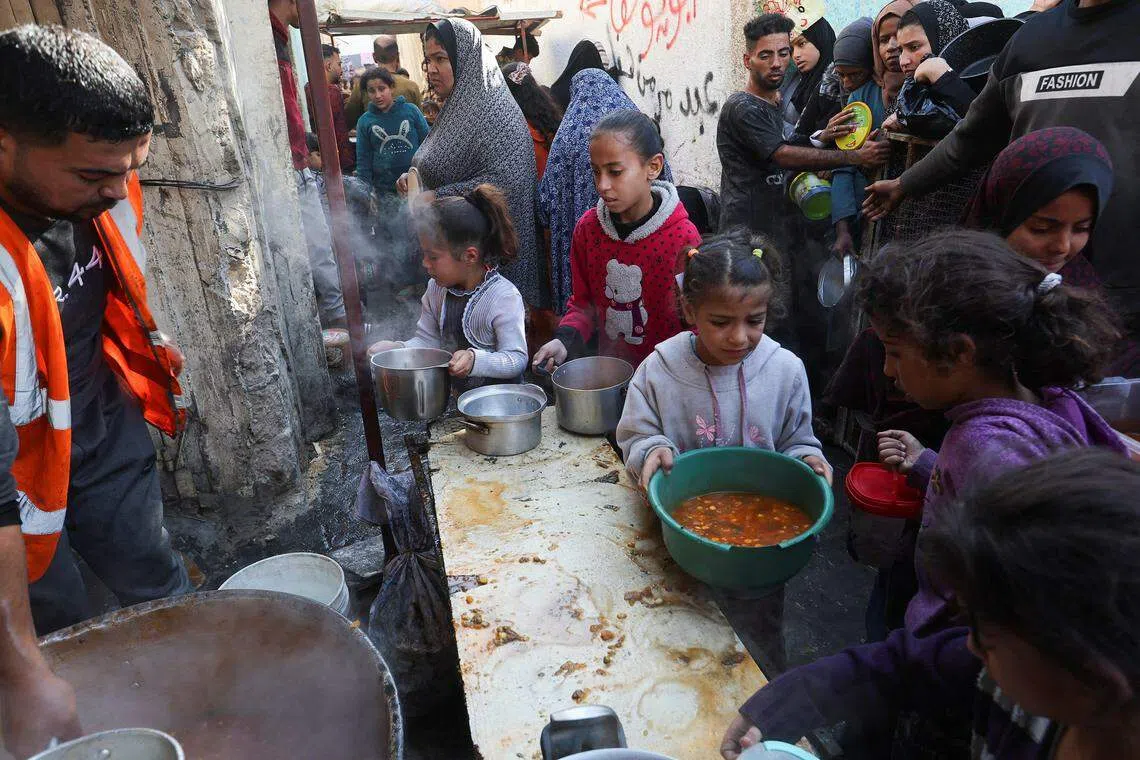 12月2日，在加沙地带南部的拉法（Rafah），巴勒斯坦人等候领取志愿者提供的食品。（路透社）