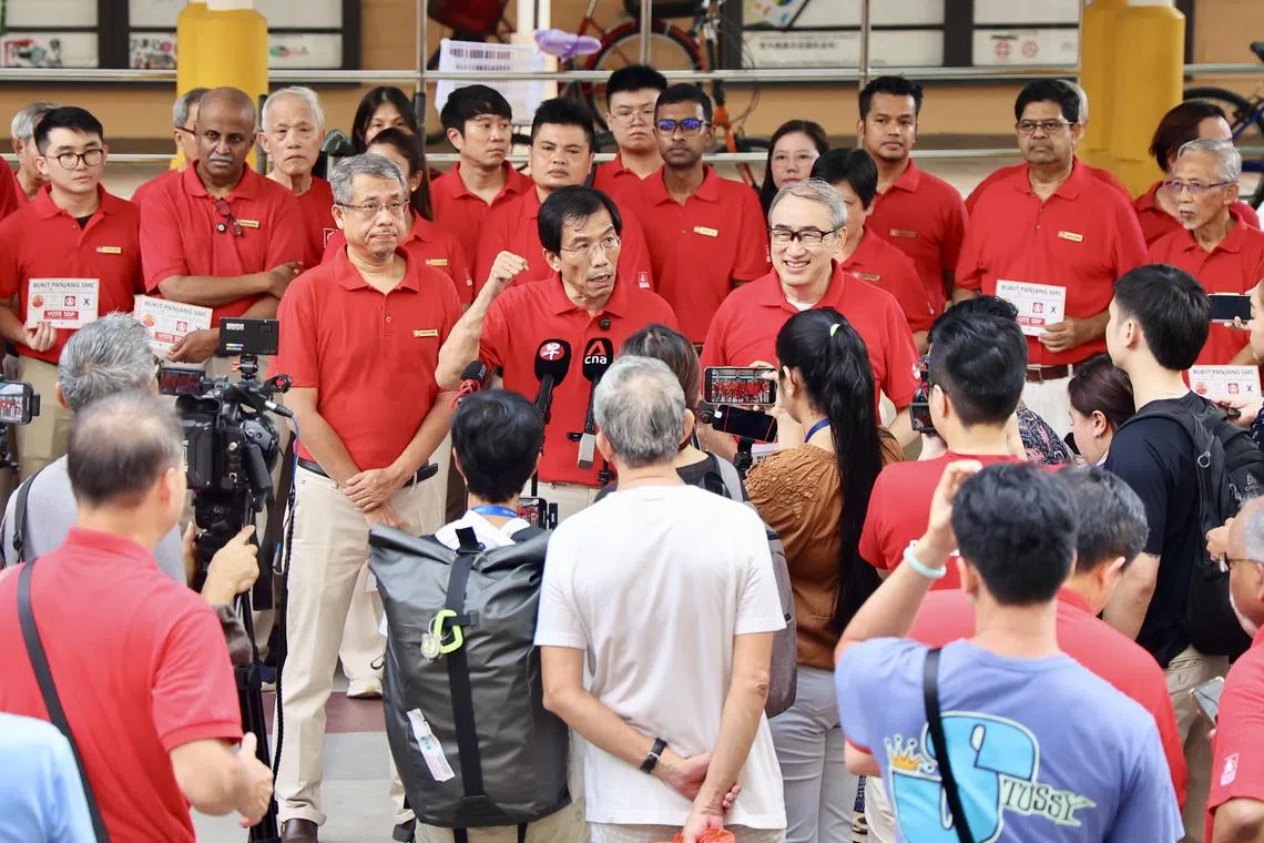 出征三巴旺集选区的新加坡民主党党员达曼胡理（中左起）、秘书长徐顺全，以及党员陈威儒，星期六在万吉组屋区公布竞选口号。（陈斌勤摄）