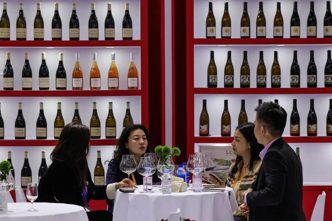 第八届中国国际进口博览会在上海举行期间，中国民众在一家红酒展位旁品酒。（路透社）