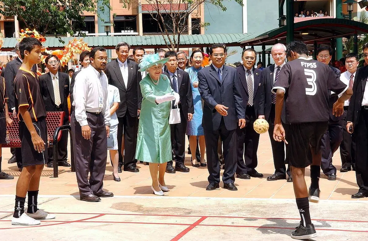 英女王2006年走访大巴窑7巷时与居民互动，还尝试向玩藤球的青年发球。（档案照片）