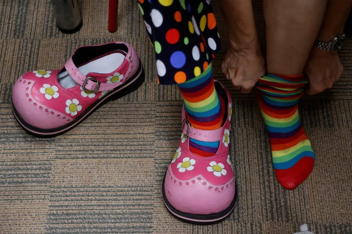 小丑义工在造型上下功夫，挑选设计独特的鞋子来搭配服装。（林明顺摄）