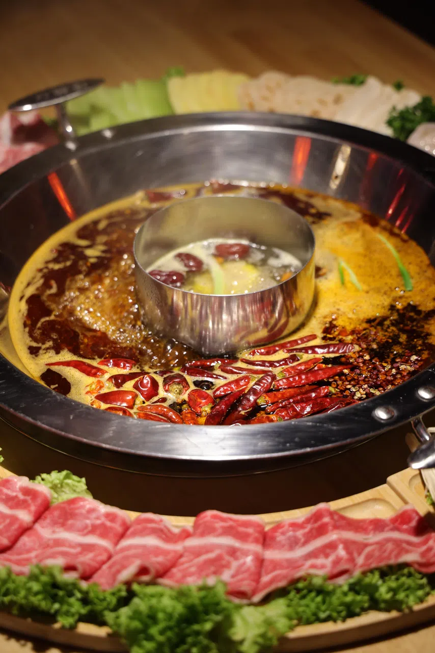 哈佛汤鸳鸯锅上桌时，店员在招牌红锅中倒入老鹰茶，据说有缓解燥热的功效。（餐馆提供）