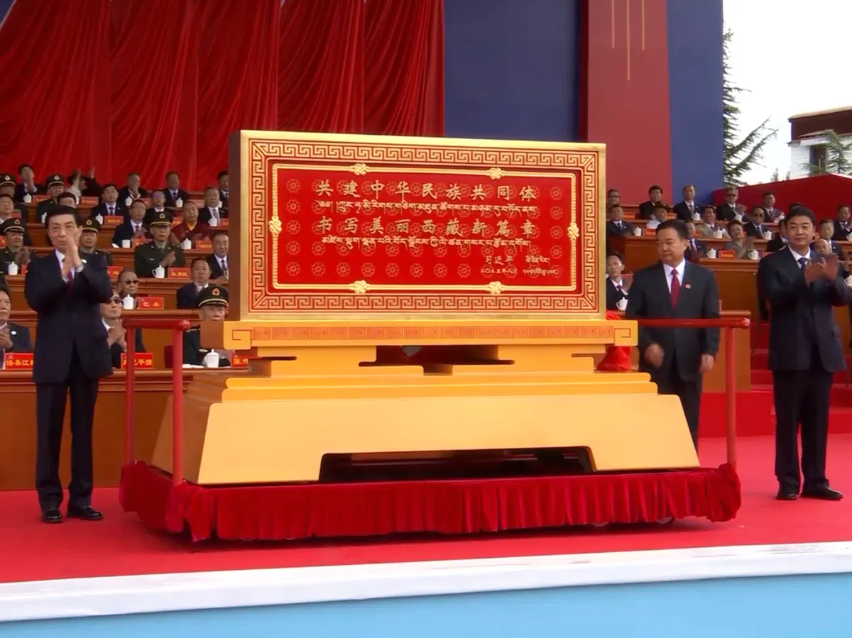 中国全国政协主席王沪宁（左一）在西藏自治区成立60周年庆祝大会上，向西藏自治区赠送中国国家主席习近平题词的贺匾。（央视新闻视频截图）