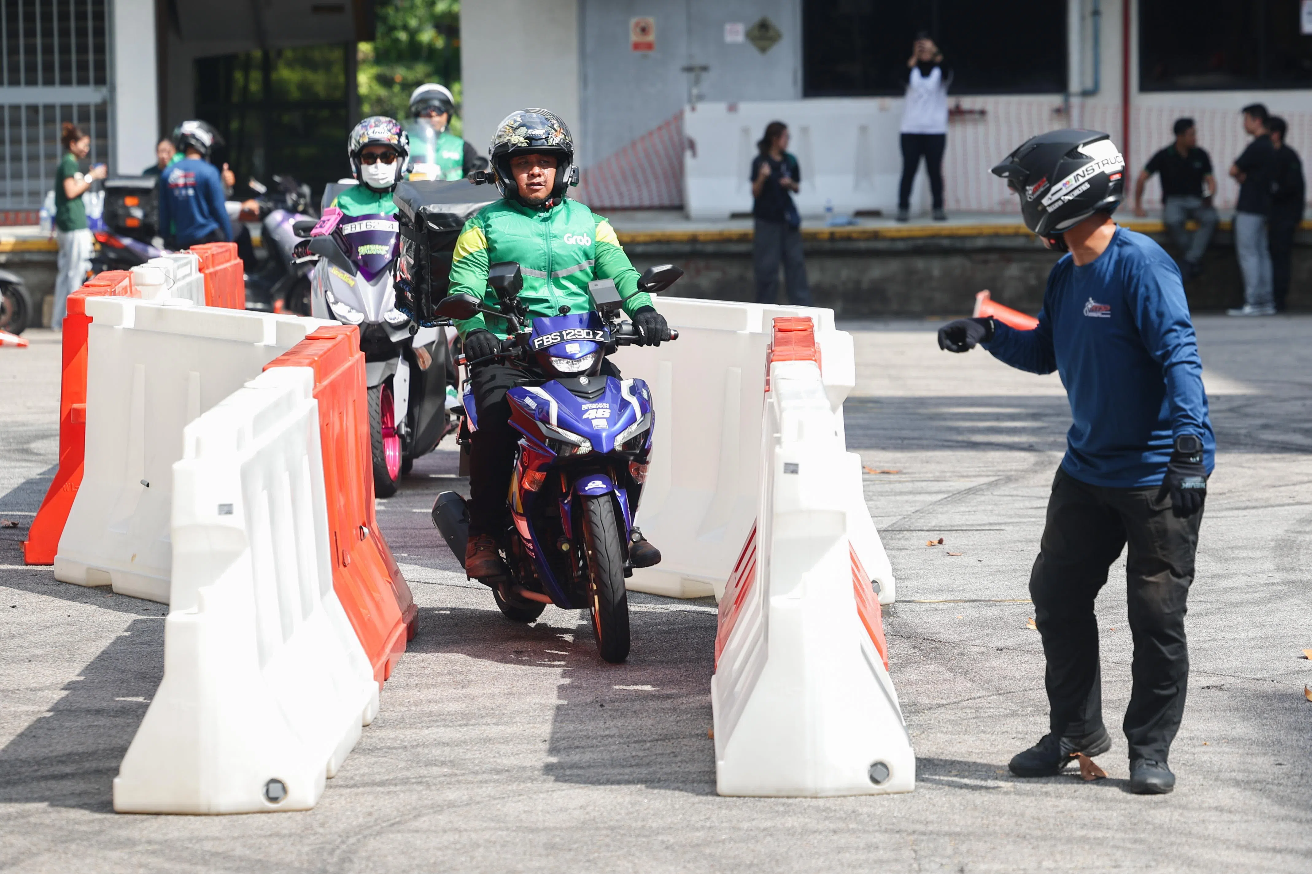 参与课程的送餐员须在狭窄的道路行驶，新加坡骑行安全协会教练在一旁全程指导。（蔡家增摄）