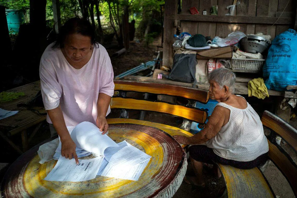 在泰国中部的猜纳府，为了耕作而借贷的58岁米农西拜让记者看她家的债务清单。（路透社）