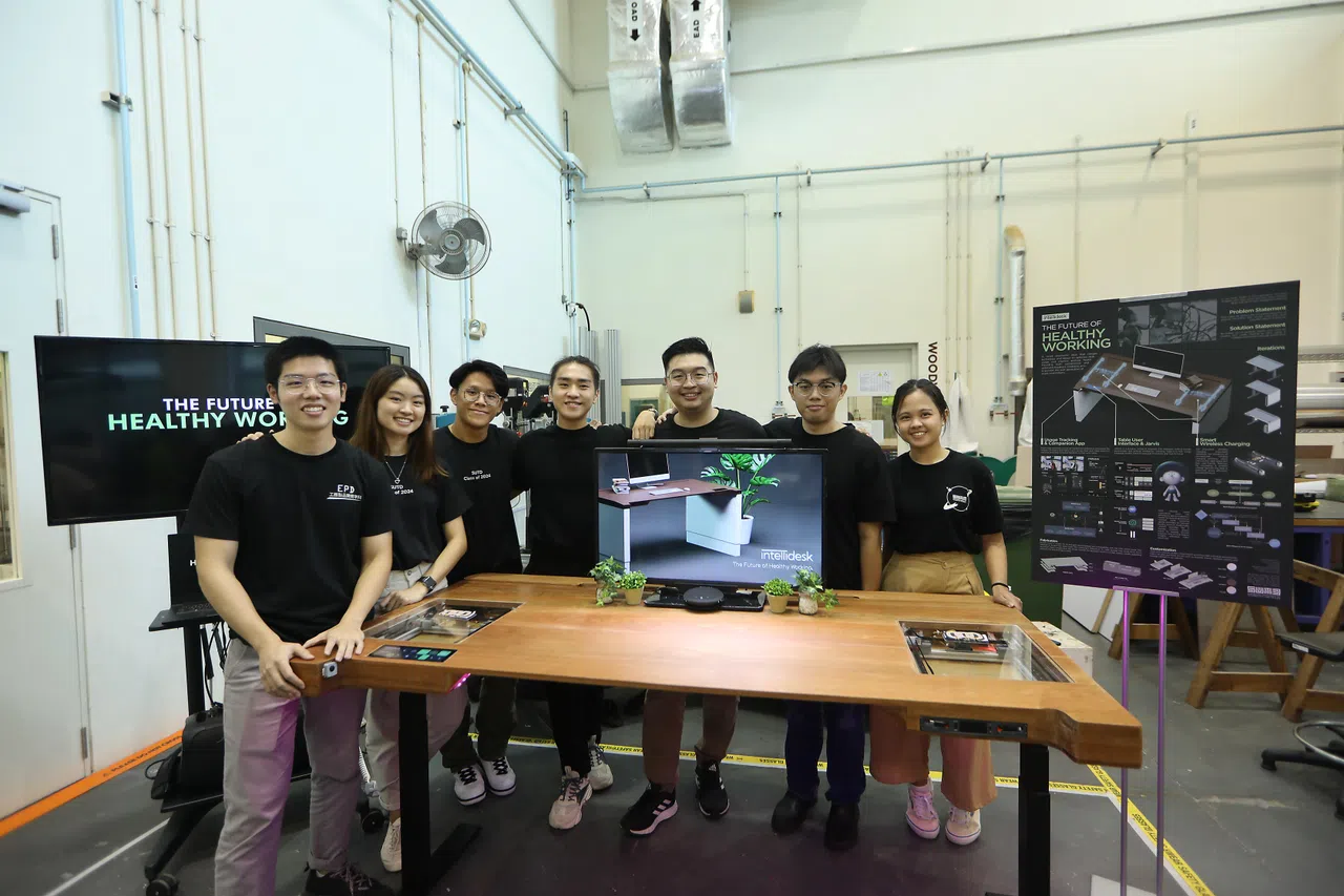 由傅雄炜（左起）、郭秀怡、严景耀、赖品年、严伟德、傅建华和法蒂玛组成的七人团队设计出一款智能人体工学办公桌。（陈心媛摄）