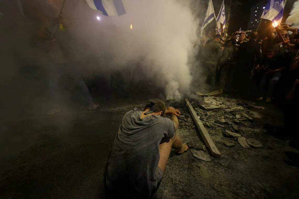 其中一名抗议者坐在混乱的人群中，交叉手臂模仿人质被虏的情况。（路透社）