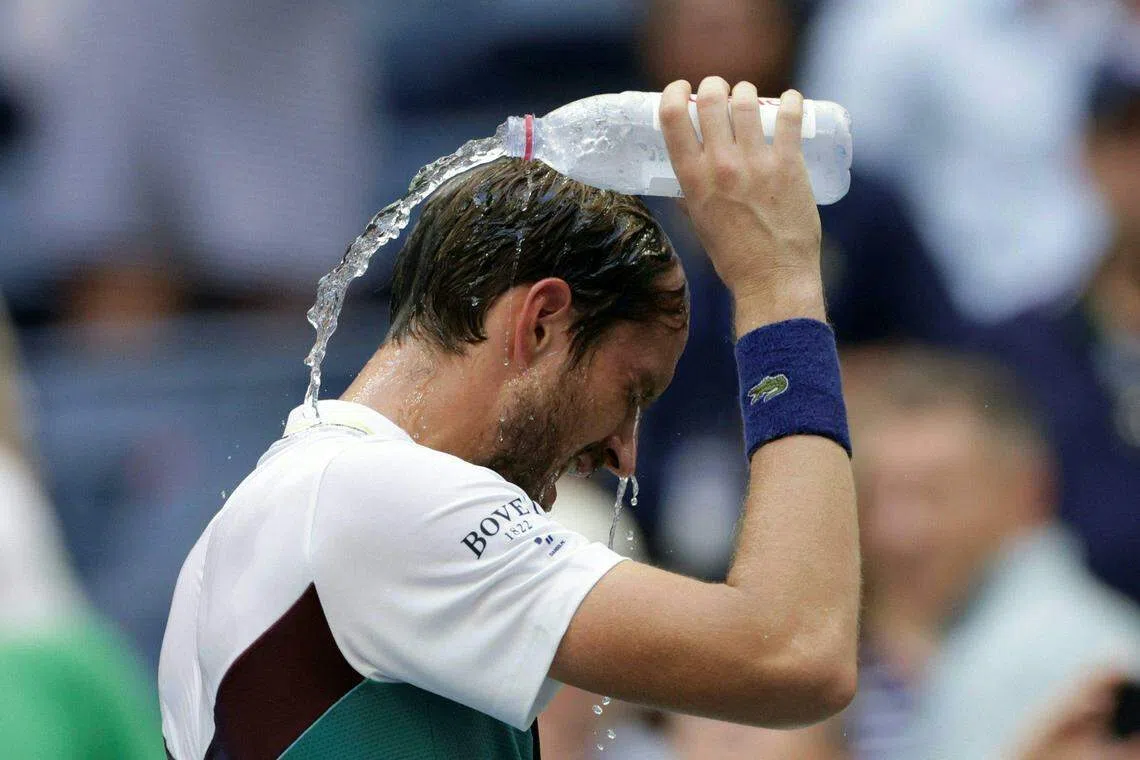 天气酷热，梅德韦杰夫在比赛结束后，往头上倒水。（法新社）