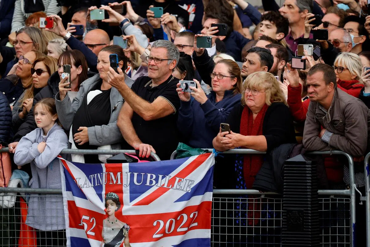 女王灵柩队伍经过时，民众纷纷举起手机相机，记录历史性的一刻。（路透社）