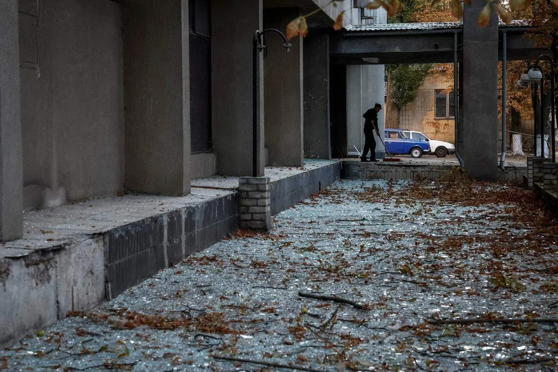 基辅这栋大楼的玻璃窗在星期天的无人机袭击中被震碎，图为工人在清理满地的玻璃碎片。（路透社）