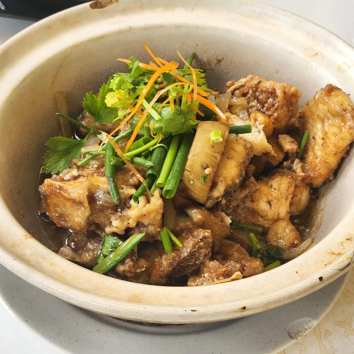 文德记煮炒的蒜香白胡椒焖鱼头加入烧肉、蒜头和茄子等，食材丰富。（陈爱薇摄）