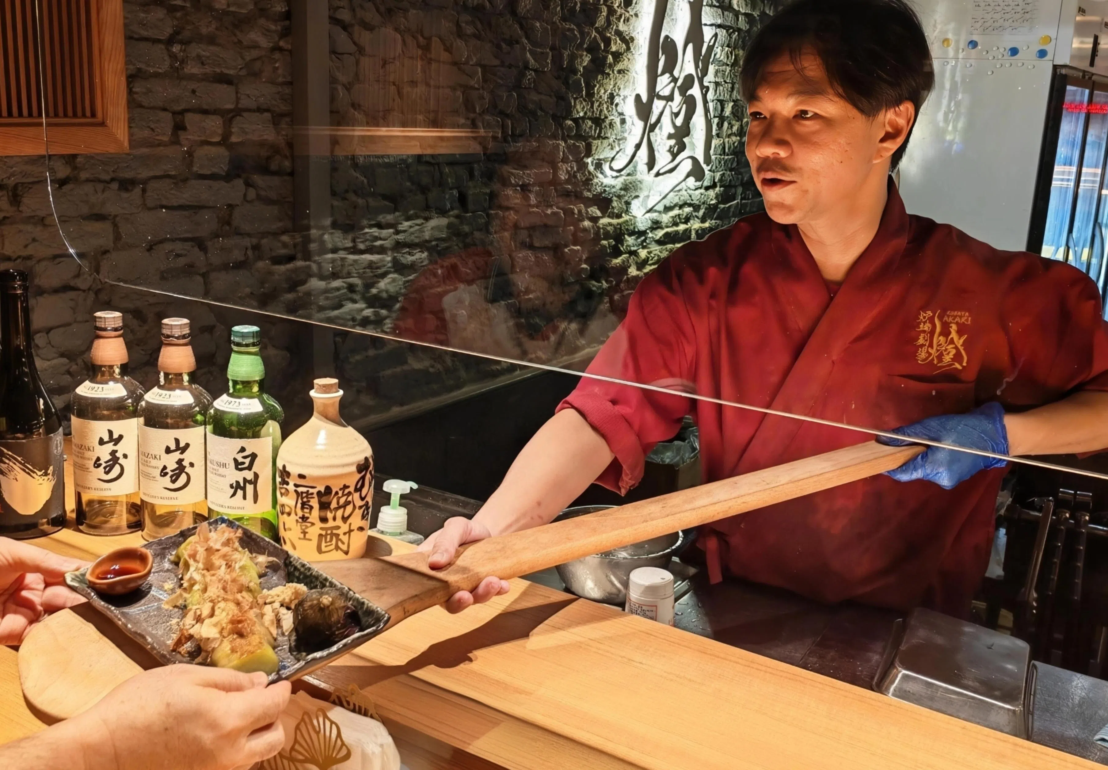 师傅循炉端烧的传统，用木制铲板将热腾腾食物送到食客面前。（陈爱薇摄）