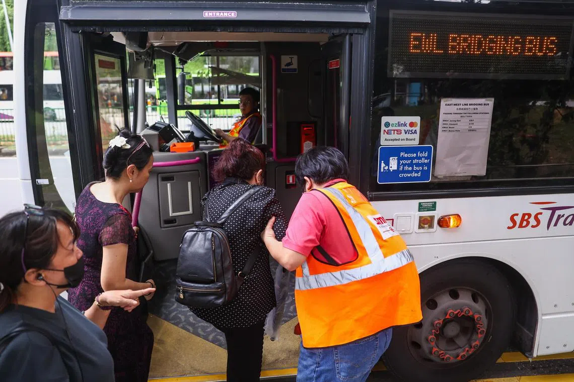 裕廊东的接驳巴士站，每五分钟至少有一辆接驳巴士接待乘客，SMRT人员也在巴士旁协助乘客上车。（白艳琳摄）