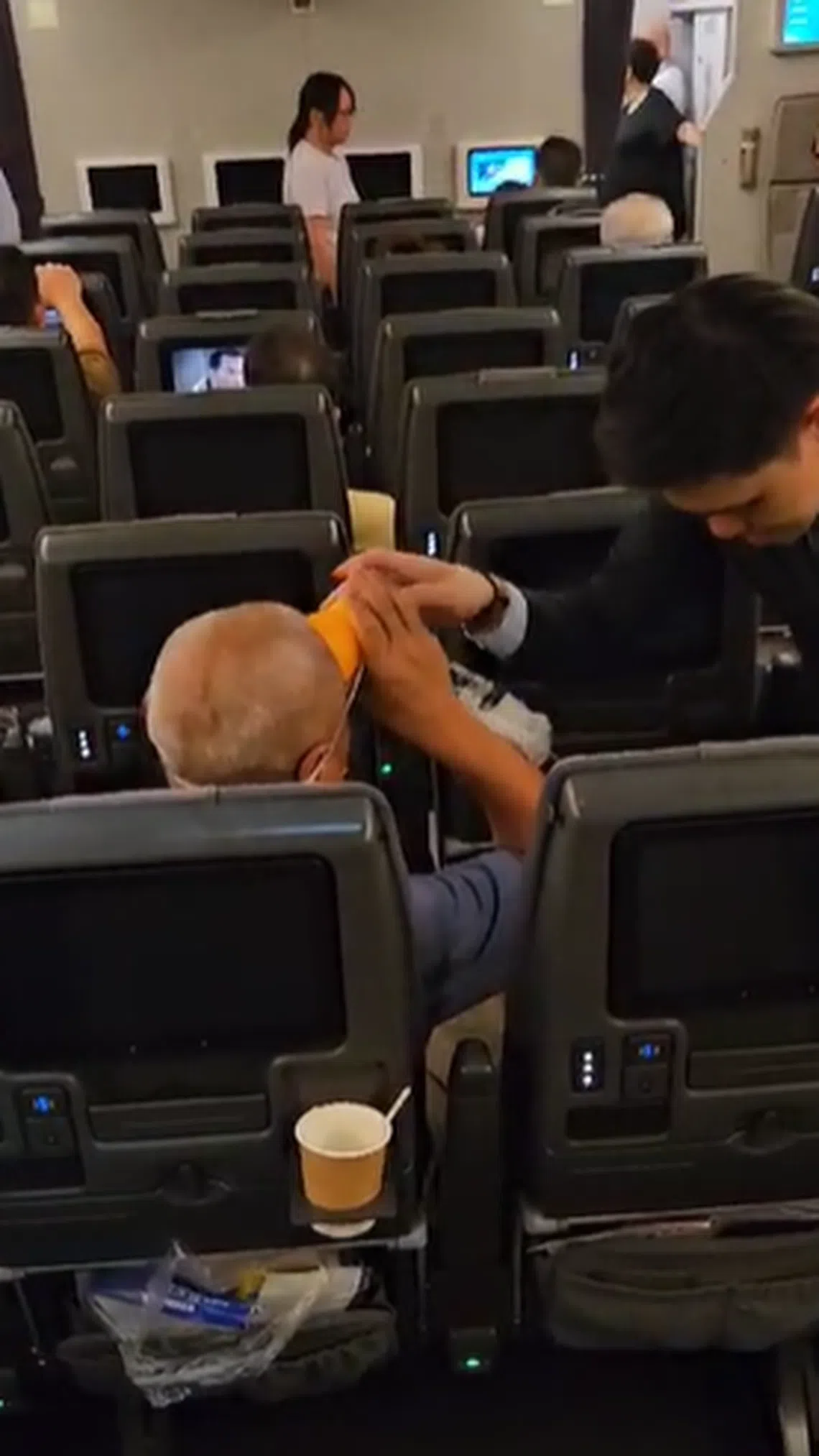 机中空气循环不佳且闷热，坐在刘臻前排的乘客需氧气面罩协助呼吸。（受访者提供）