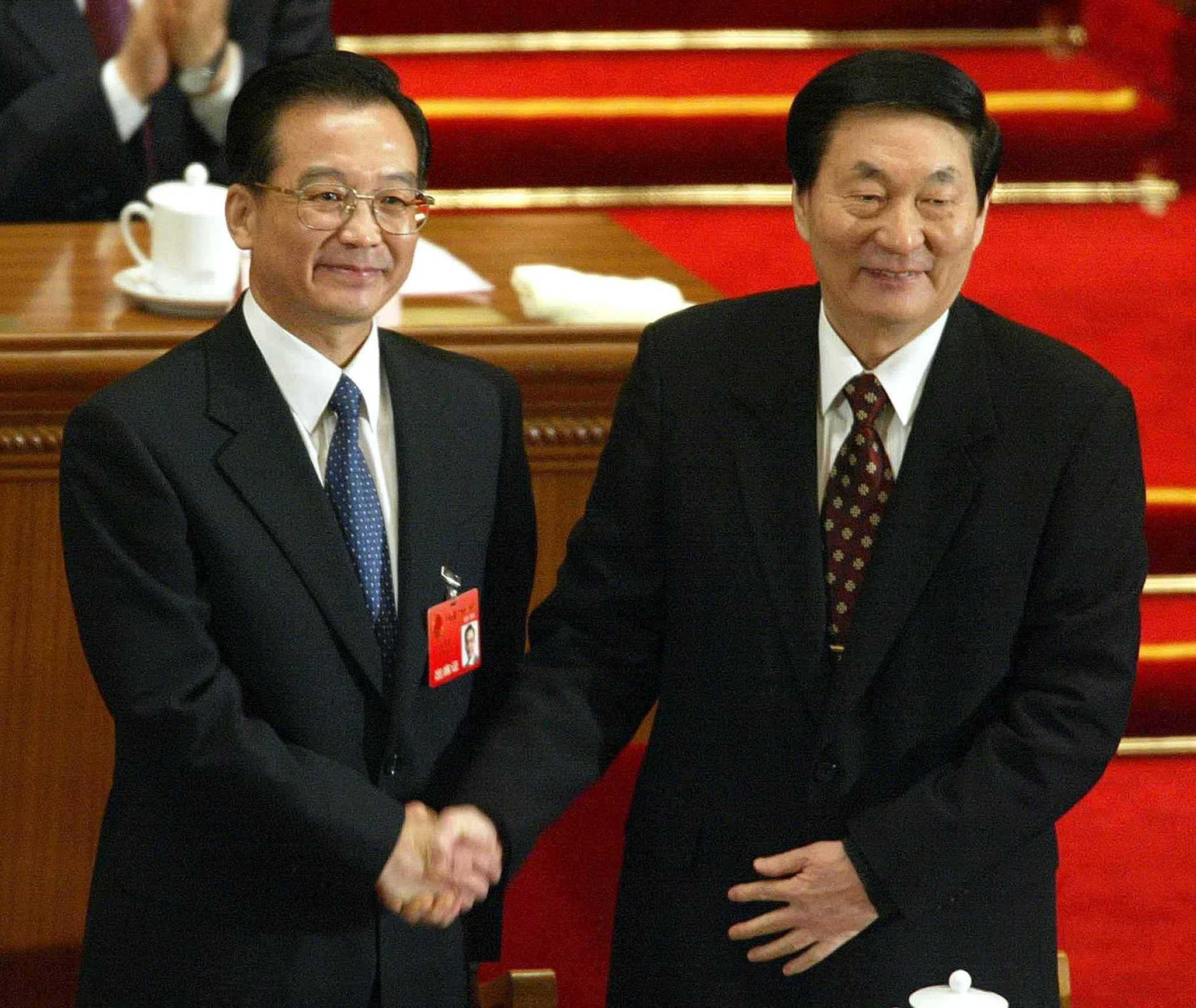 作为中国第三代中央领导集体成员之一的朱镕基（右），在2003年3月的全国人民代表大会上，将总理职务交棒给继任者温家宝（左）。（法新社）