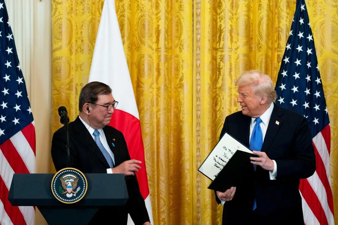 在会谈后的记者会上，特朗普（右）赠送一份礼物给石破茂。（彭博社）