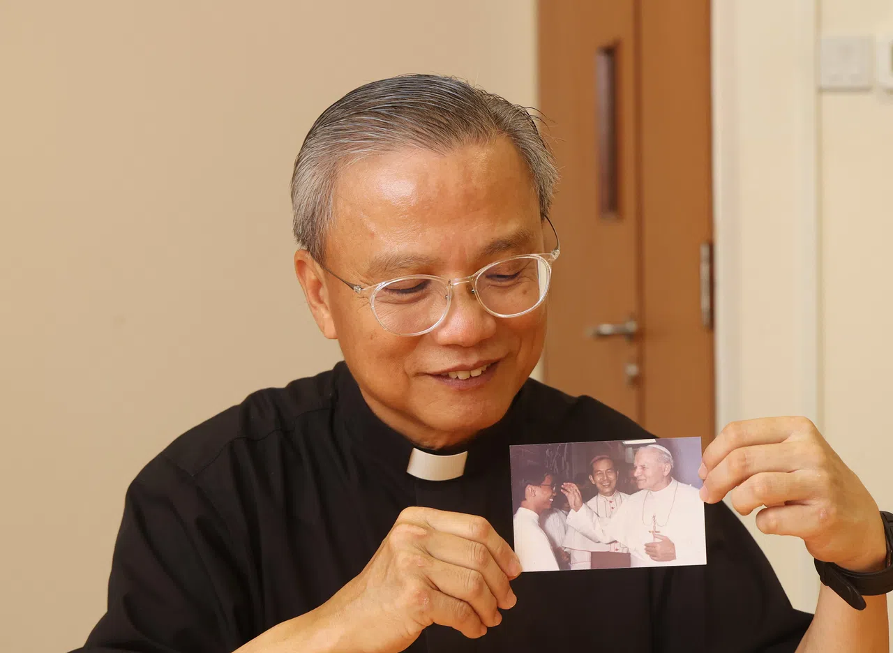 圣十字架堂主任神父萧永伦展示一张摄于1986年的照片，显示当时的教宗若望保禄二世主持弥撒后，在后台逐一与辅祭员打招呼。萧永伦是其中一名有机会与教宗交流的修生。（唐家鸿摄）