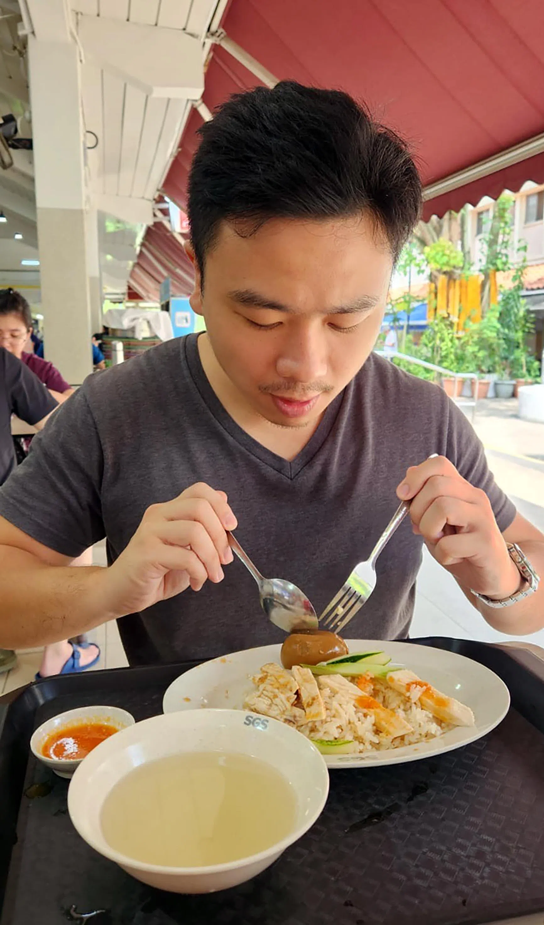 红点同心党新人梁凯杰在冷静日到裕华村巴刹和熟食中心吃鸡饭。（受访者提供）