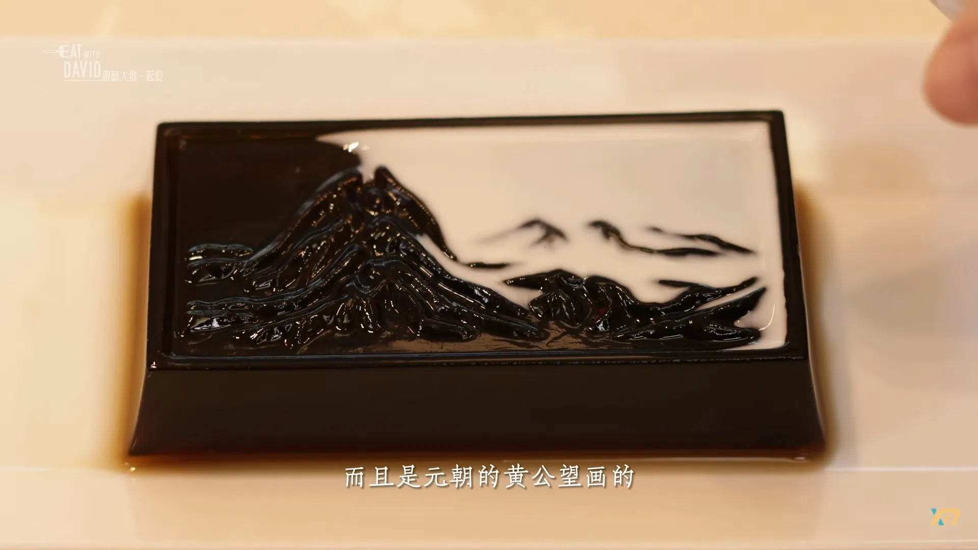用仙草做成的“富贵山居图”倒入牛奶后，缓缓显现山峦的模样。（网络截图）