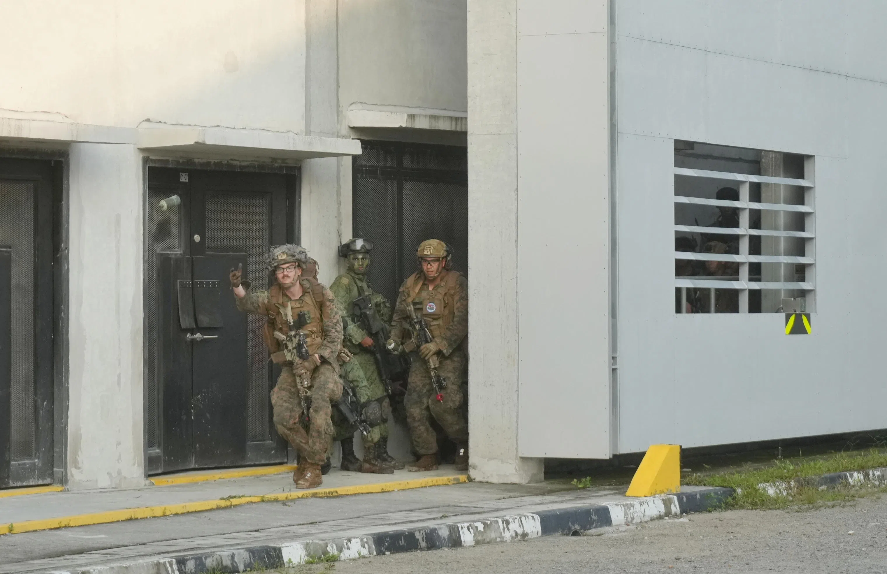 星期三上午，新加坡陆军部队和美国海军陆战队在军训城进行演训，双方组成的联合特遣队在建筑物之间移动，美军人员（左一）抛出烟雾弹作为掩护。（谢智扬摄）