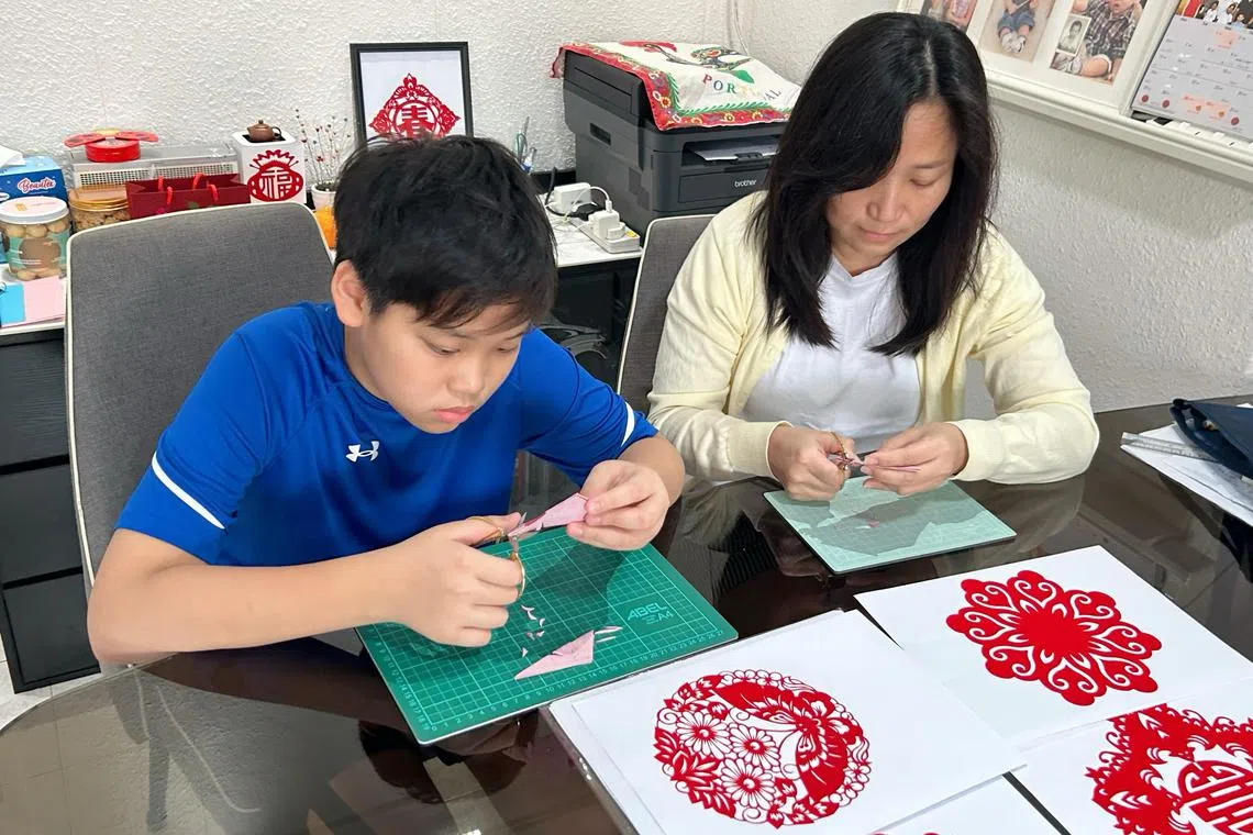 谢悦清带着儿子剪纸，趁机教育他寄贺卡的传统。（受访者提供）