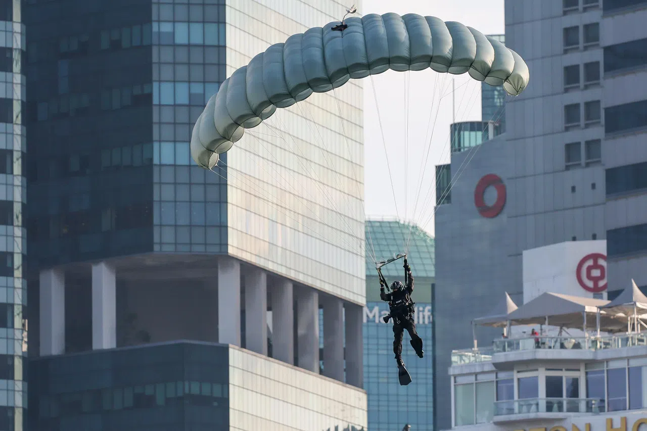 蛙人模拟作战程序，每人背着近60公斤重的防水器材和枪支，极速降落。图为星期六（7月5日）第二场国庆庆典国民教育演出画面。（张俊杰摄）