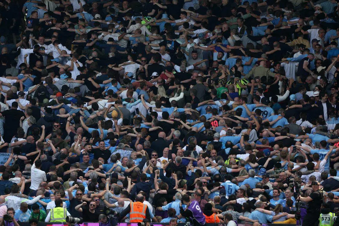 曼市球迷在格瓦迪奥尔攻入第三球后，高兴地搭肩连成一线庆祝。（路透社）