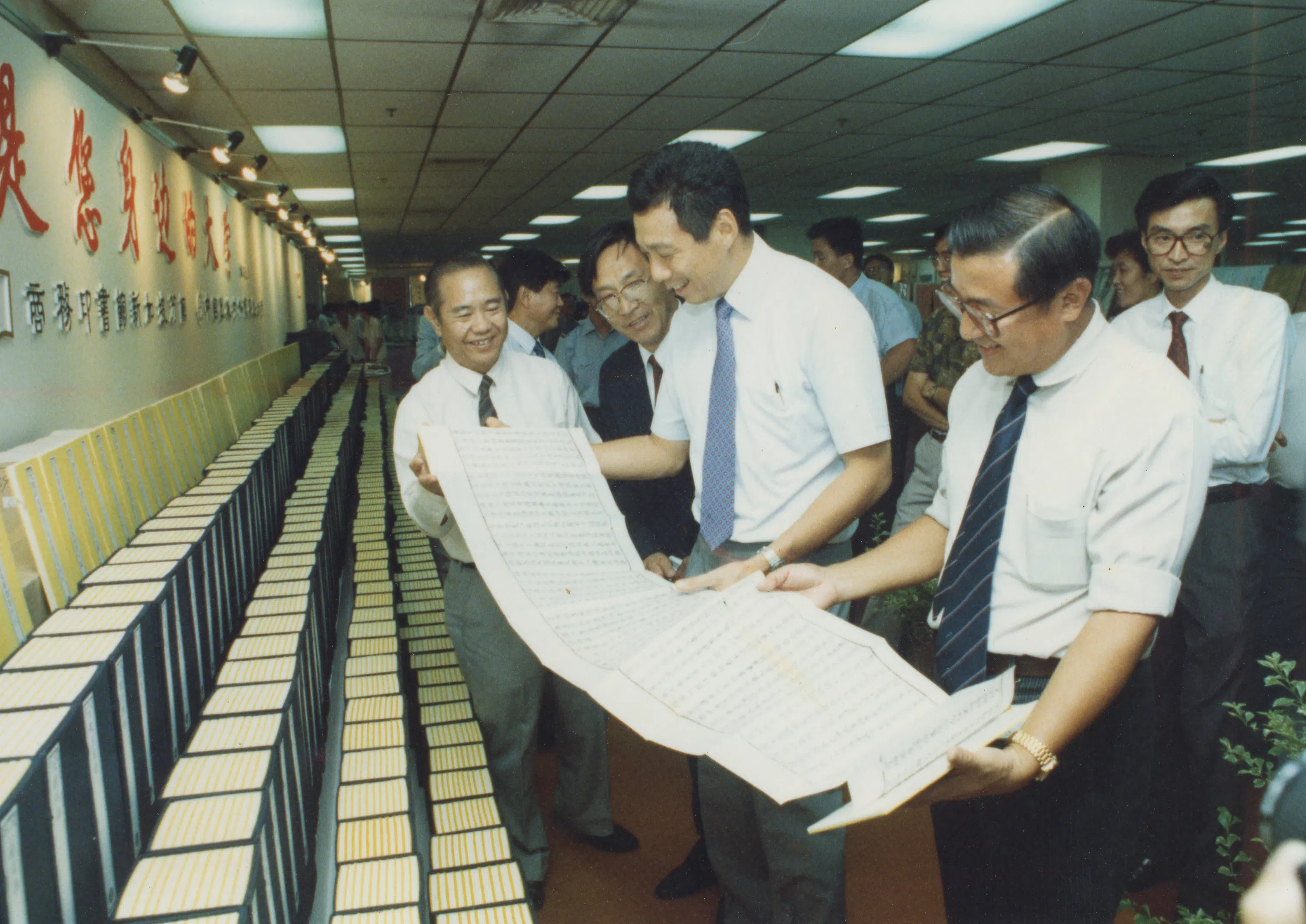 黄锦西带领华文报集团走过最艰难的1980年代，于1991年卸下华文报集团总经理的职务，挥别报业控股。图为他离职前一年举行的第五届世界华文书展上，与开幕礼主宾、时任贸工部兼国防部第二部长李显龙准将（右二）一起阅读《乾隆版大藏经》的其中一册。（档案照片）