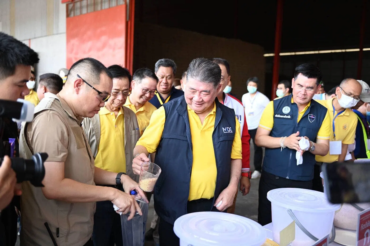 泰国副首相兼商务部长蓬探（中）星期一（5月7日）带领团队和媒体走访储存前首相英叻政府囤积大米的仓库，并在记者面前食用这些旧米煮出来的白饭。（取自泰国商务部脸书）
