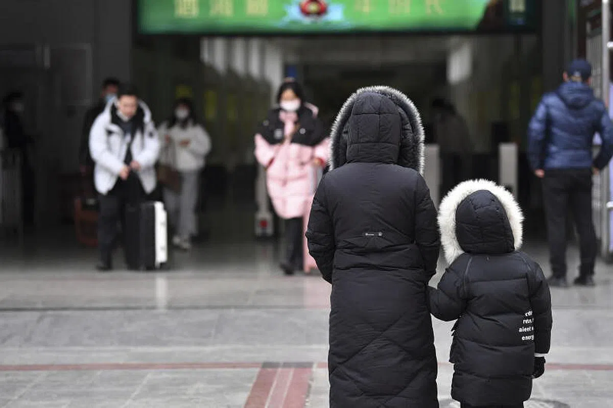 一位女士带着孩子于1月16日站在兰州火车站西出站口。（新华社） 