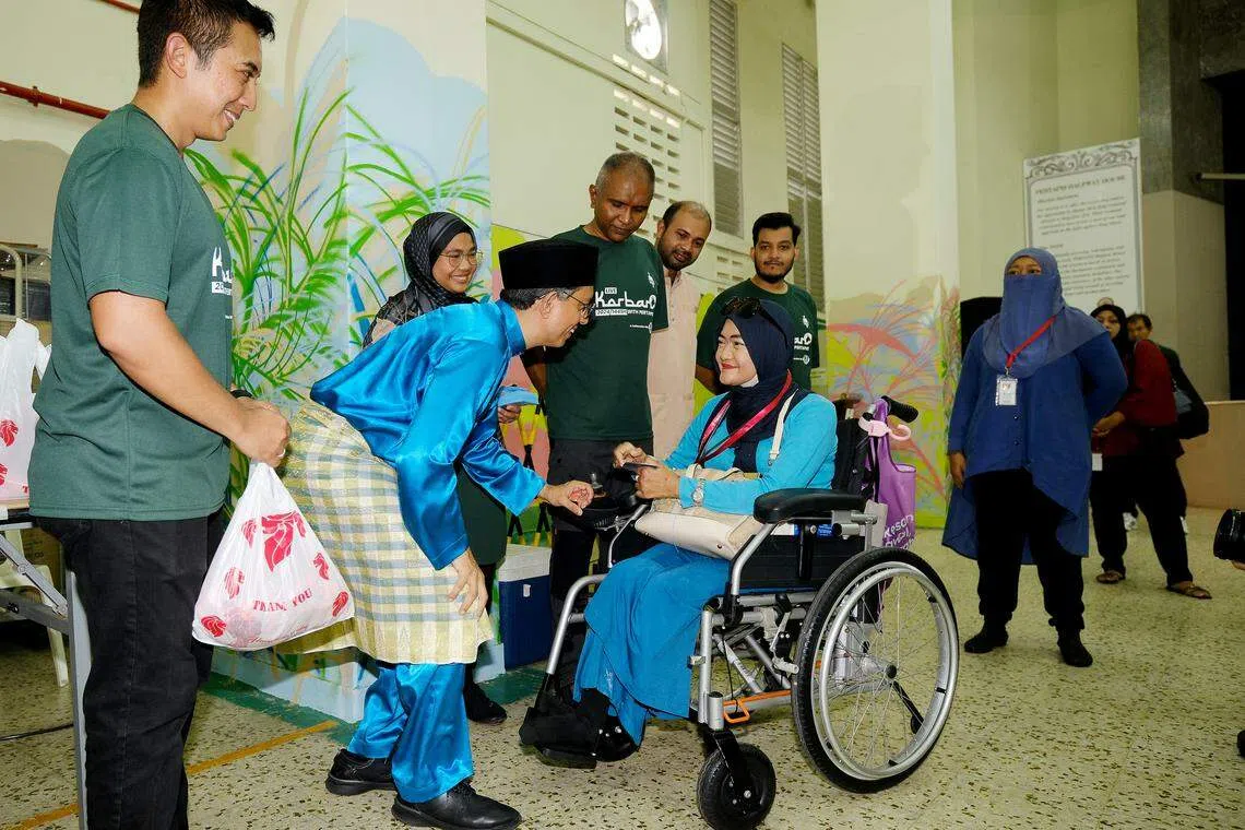 内政部兼国家发展部政务部长费绍尔副教授（左二）到宰牲仪式现场，为居民们分发羊肉与日常食品礼袋。（曾坤顺摄）