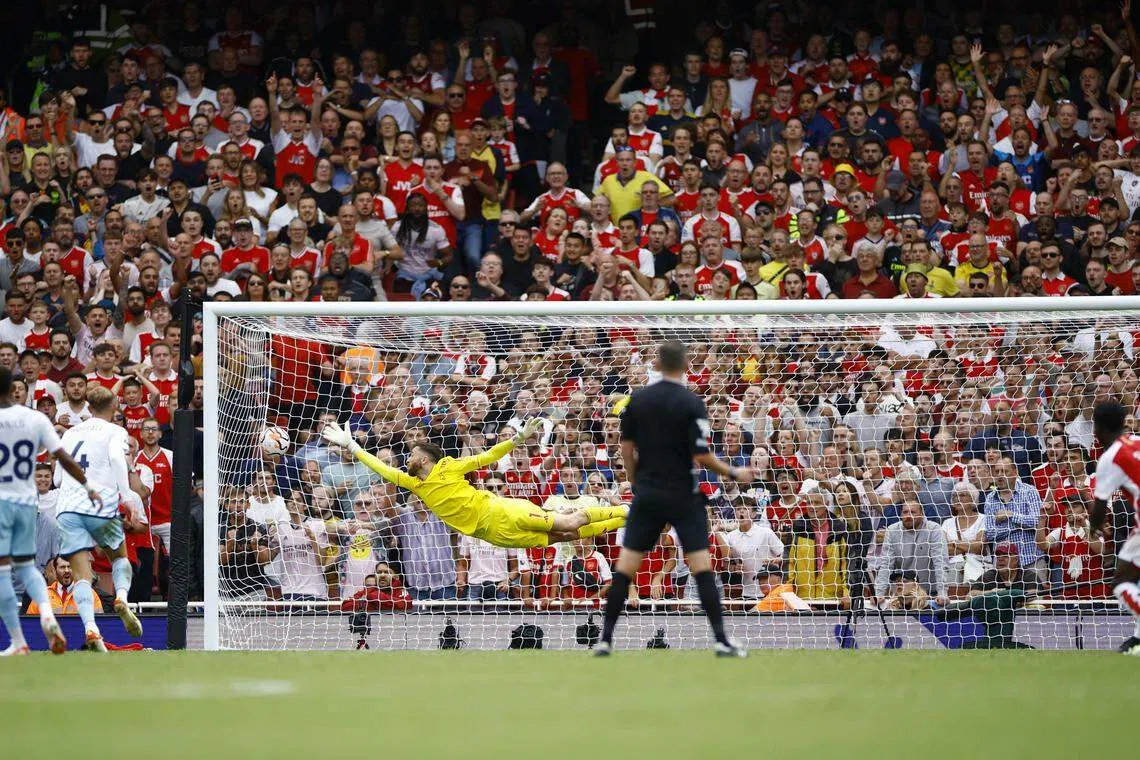 萨卡（红衣7号）一记刁钻远射，让前队友特纳（黄衣）即使伸长手臂，飞身扑救也无能为力。（路透社）