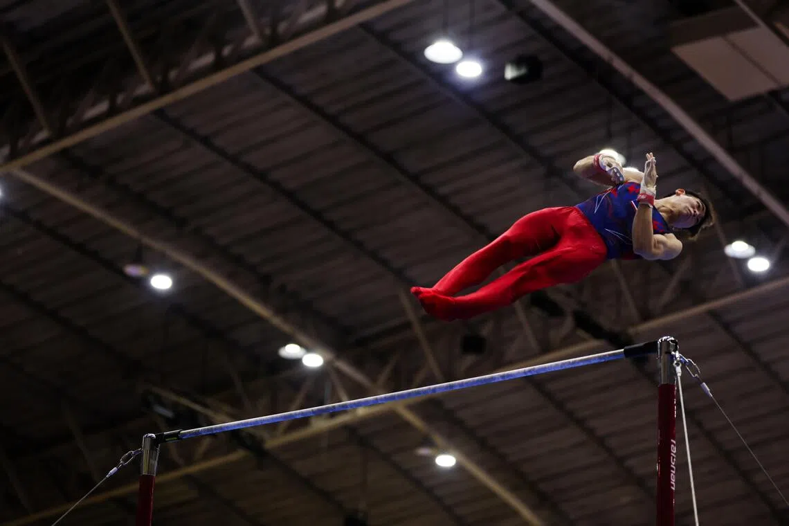 男子体操单杠赛场上，选手轻盈翻转，稳健握杠，动作干净利落。（白艳琳摄）