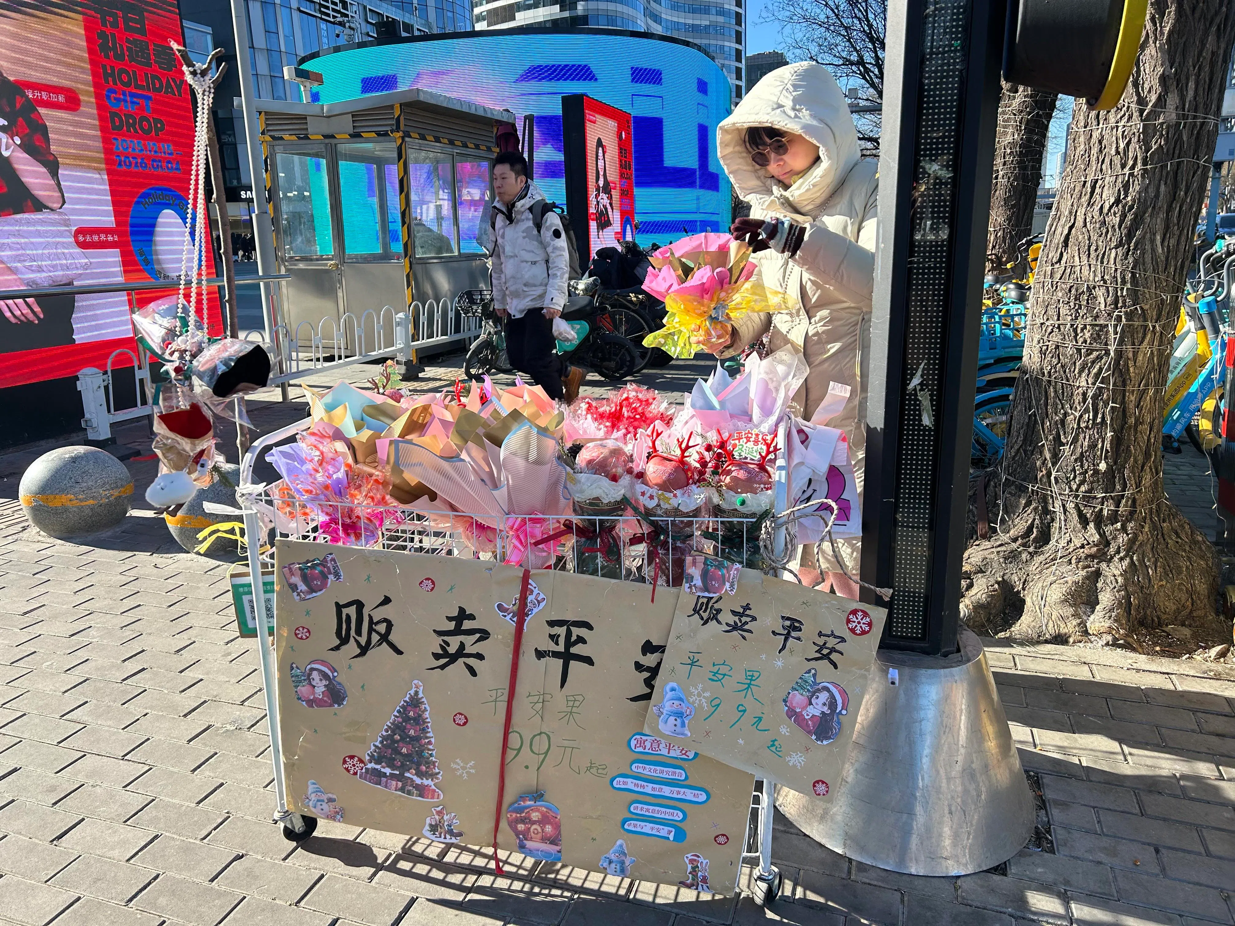 经营糕点生意的小刘，在北京三里屯十字路口旁摆摊售卖平安果。（周岳翔摄）