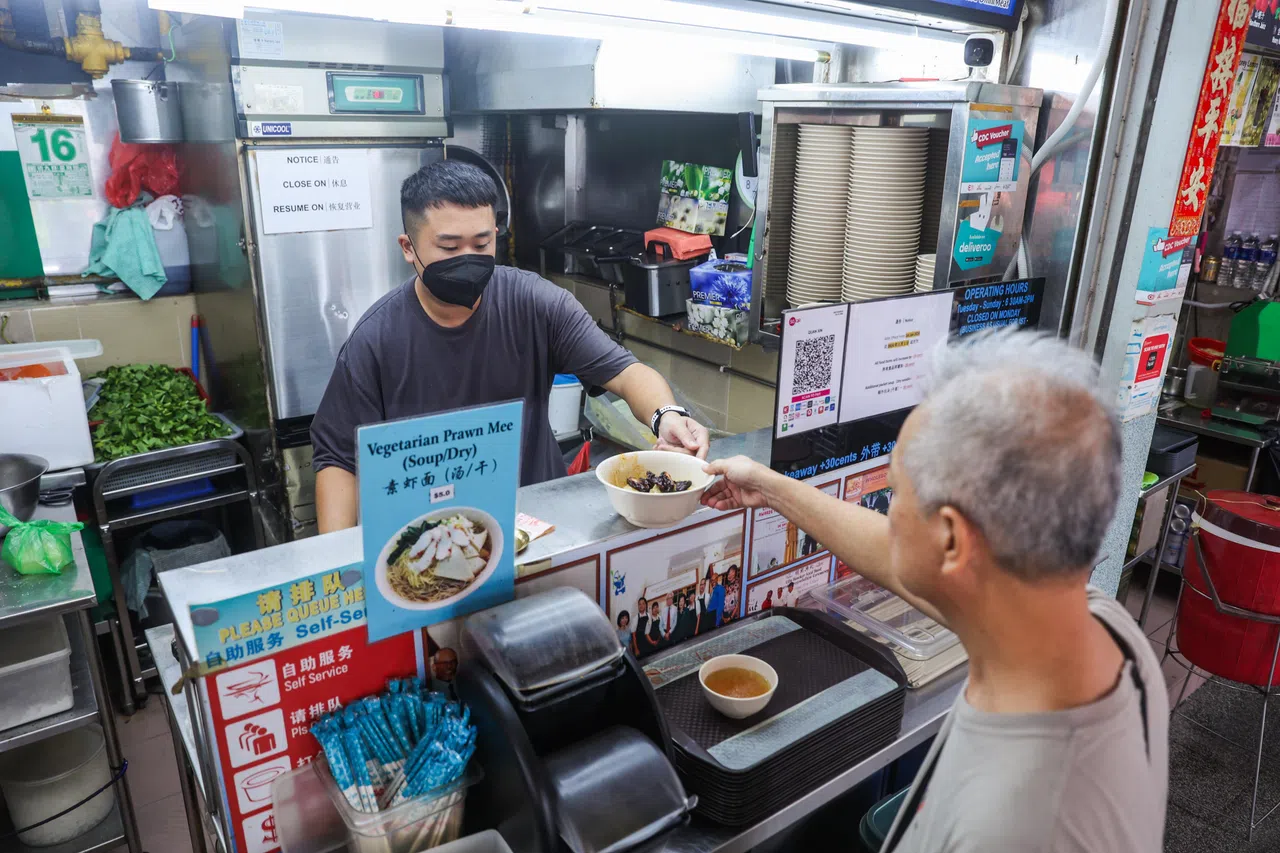 泉心素食园第二代摊主赖义学为星期三黄循财总理的就职仪式烹煮素食，虽然一直忙到凌晨过后才回家，第二天早上他照常开档，为食客准备素食。（白艳琳摄）