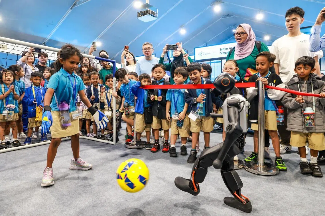 在机器人节活动现场，公众可在四大体验区亲身感受机器人技术的发展，并与机器人互动，与机器人踢足球就是其中之一。（陈斌勤摄）